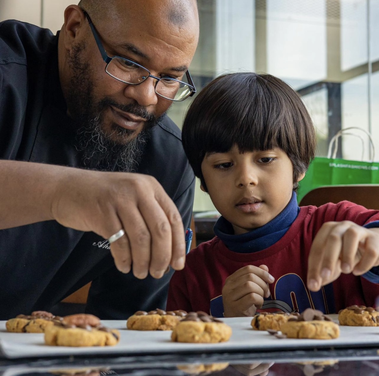 Chef Ahmed Badaoui transmettant le geste cuisine à un jeune élève lors d'un atelier pédagogique
